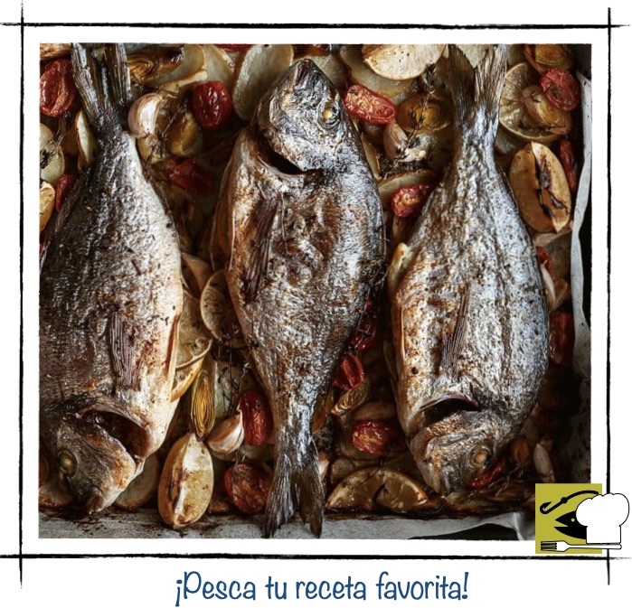 Tres doradas enteras cocinadas al horno sobre una cama de patatas, tomates cherry y ajos.