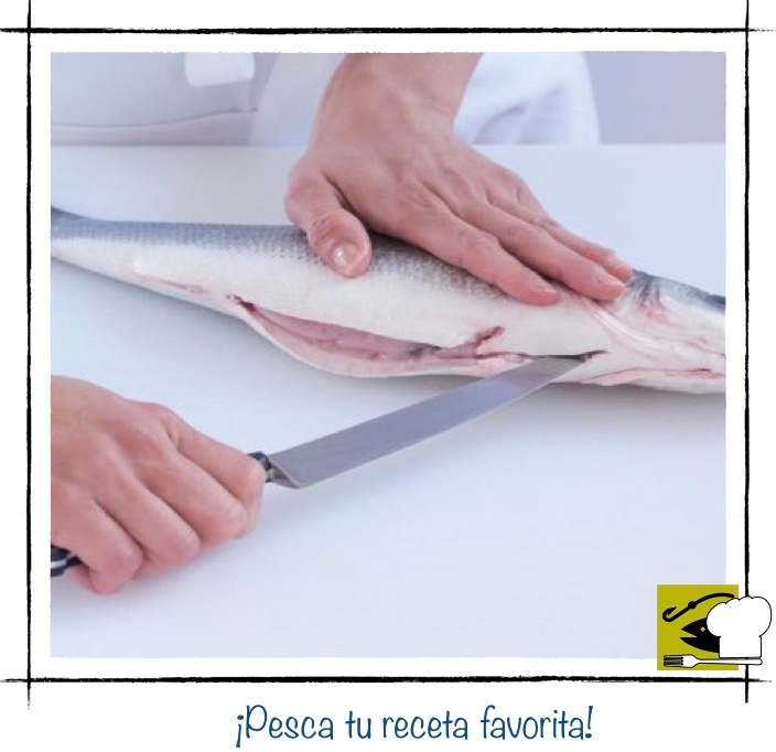Una persona deslizando el cuchillo por el vientre del pescado para abrir la cavidad abdominal.